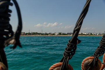 View of the Mediterranean coastline with blue water through the rigging of a sea vessel. Cyprus. Rest at the sea. Cruise