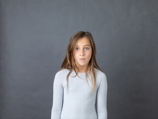 Portrait of a young suprised girl on grey background.