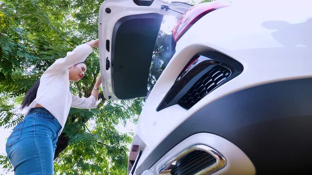 Young woman open and close trunk of car for finding something. Low angle view. 4K