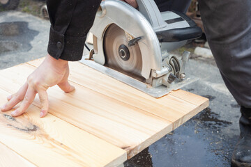 in men's hands an electric saw and it cuts light boards