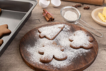 Traditional christmas gingerbread cookies over a wooden table with sugar and ingredients