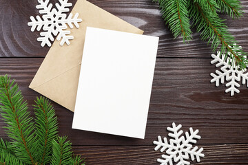 Christmas or New Year greeting card mockup with envelope, white snowflakes and fir tree branches