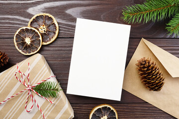 Christmas greeting card mockup with gift box, dry oranges, cones and fir tree branches