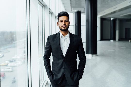 Solid look, handsome Indian man in black suit in modern room, handsome arab businessman