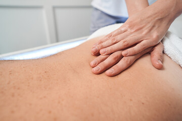 Masseuse hands massaging man back in spa salon