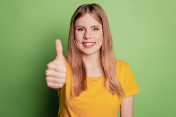 Portrait of promoter reliable lady demonstrate thumb up wear yellow t-shirt isolated on green color background