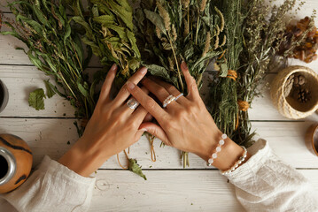  bunch of dried medicinal herbs in women's hands,  collection of medicinal herbs, white wooden table