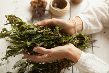  bunch of dried medicinal herbs in women's hands,  collection of medicinal herbs, white wooden table
