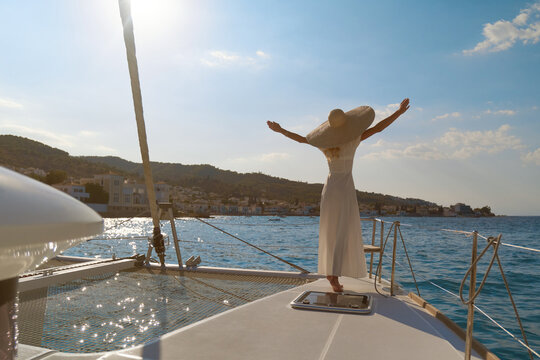 Beautiful woman wearing straw hat and white dress on a yacht enjoys the journey, Spetses, Greece, Europe