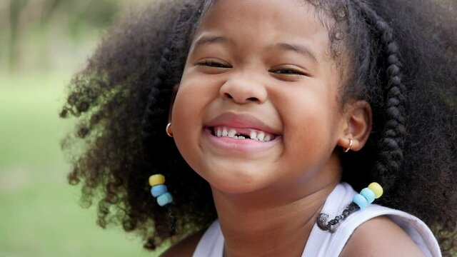 Portrait Little African girl with curls smiling sincerely white teeth looking at camera ,happy cute child has fun. 