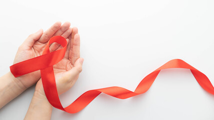 World AIDS day in December month campaign. Human hands holding red ribbon awareness on white...