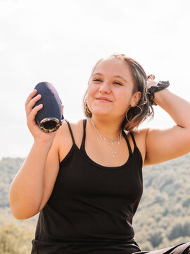 Cheerful woman with portable speaker in highlands