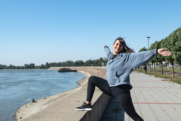 Young happy carefree self-loved and self-aware yoga fitness woman is active and practices yoga outside on a sunny autumn day. Runner woman stretching her muscles outdoor before running sport exercise