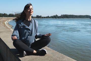 Young happy carefree self-loved and self-aware yoga fitness woman is active and practices yoga outside on a sunny autumn day. Runner woman stretching her muscles outdoor before running sport exercise