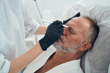 Male person having cleansing skincare procedure in cosmetology clinic