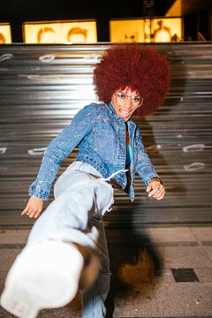 Stylish woman kicking air on dark street
