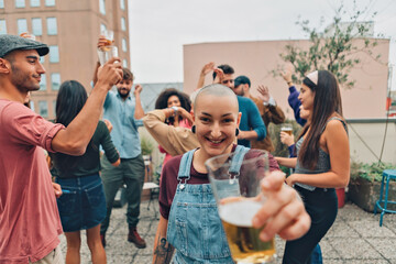 smiling hipster girl at the party - cheerful young woman cheering - young alternative lady stretches her arm offering a sip of beer to friends