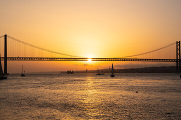 Fototapeta na wymiar Vivid colorful sunset in a river with a bridge and a sailing boat