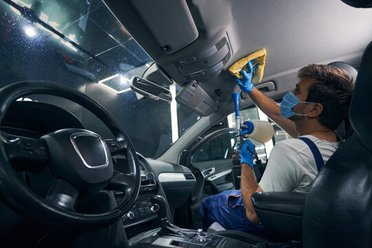 Man with dry cleaning apparatus taking care of car ceiling