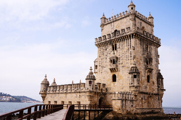 Fototapeta na wymiar Historical sone tower and bridge next to the river in Lisbon