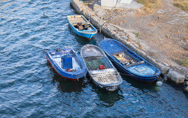 Obraz premium old and dirty rowboats moored to concrete pier
