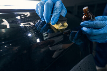 Repairman applying ceramic coating to car surface - obrazy, fototapety, plakaty