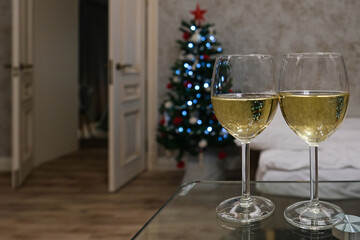 Two glasses of champagne on the table against the background of a Christmas or New Year tree