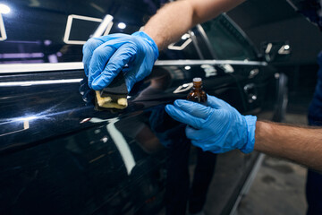 Person applying coating on car surface scratches - obrazy, fototapety, plakaty