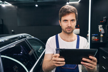 Caucasian male mechanic with tablet looking to camera