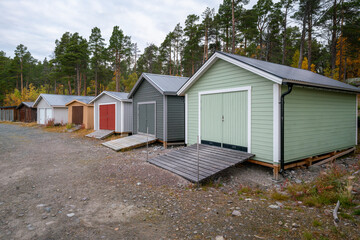 Fototapeta na wymiar Colorful wooden houses to keep the boats in on the lake shore. Stora Sjofallet National Park, Sweden.
