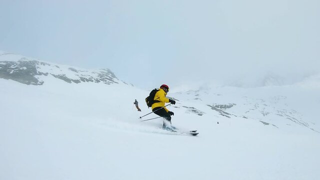 Man in yellow jacket ski's down a mountain on a cloudy day in Laax, Switzerland