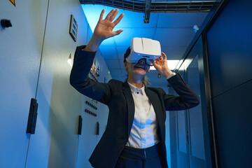 Happy young woman using virtual reality headset indoors