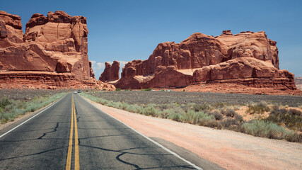 On a road approaching red sandstone cliffs in Arches National Park, Utah, USA.