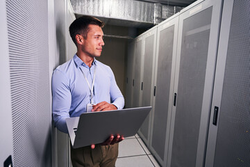 Tranquil data center worker with laptop looking away