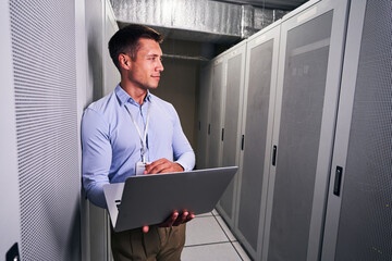 Fototapeta premium Tranquil data center worker with laptop looking away