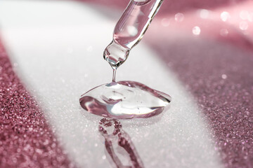 Cosmetic pipette with a pink on dark background.