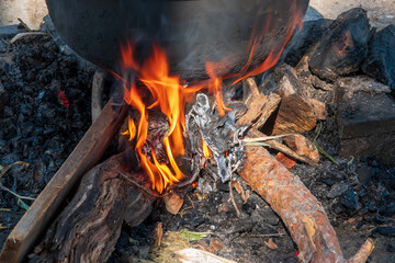 A stove on a campfire and the pot on it.
