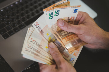 business man counting money. rich male hands holds and count cash banknotes of 50 euros bills or...