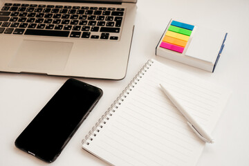 laptop, notebook, pen, colored stickers and phone on a white background. work from home. school online study. remote work. modern gadgets.