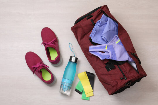 Gym bag and sports equipment on wooden background, flat lay