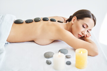 Obraz na płótnie Canvas Young female relaxing in spa salon with hot stones on her back