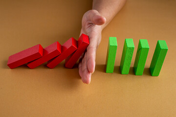 Woman's hand blocks falling wooden blocks. Crisis management in business life.