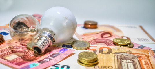 Dinero y bombillas marcando el precio de la electricidad - obrazy, fototapety, plakaty
