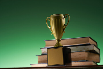 low angle view stack of books and trophy against green background