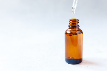Essential oil dropping from pipette to bottle. Essence liquid cosmetic. Dropper glass bottle with liquid cosmetic serum. Syrup, perfume, aromatherapy concept. Beauty Treatment