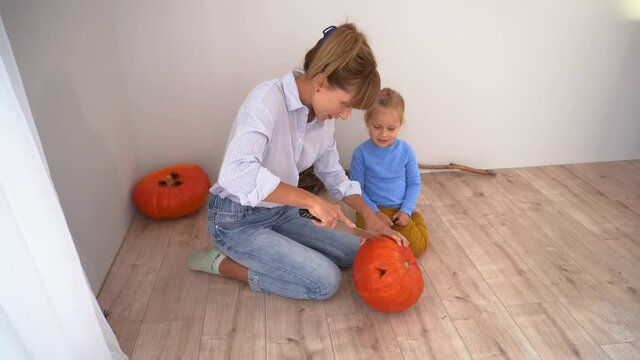 Mom and daughter carve a pumpkin for Halloween. Preparing for Halloween. Mom and daughter are having a good time.