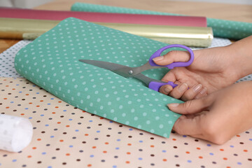 Woman cutting fabric with scissors at table, closeup