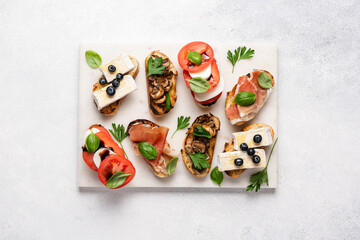 Bruschetta set with prosciutto and basil, tomatoes and mozzarella, camembert and berries, mushrooms...