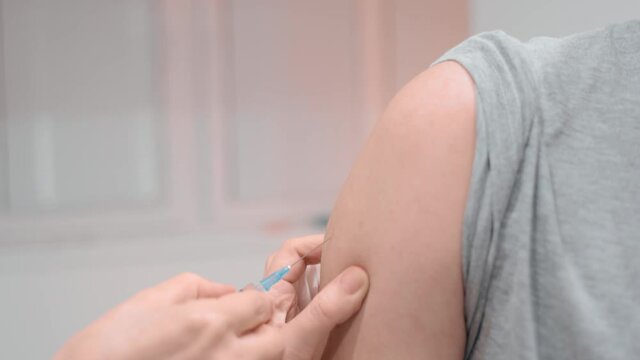 Nurse using syringe to inject vaccine to patient prevent spread of covid19.