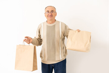 Portrait of pensioner elderly retired cheerful grey-haired man buying goods isolated over bright background